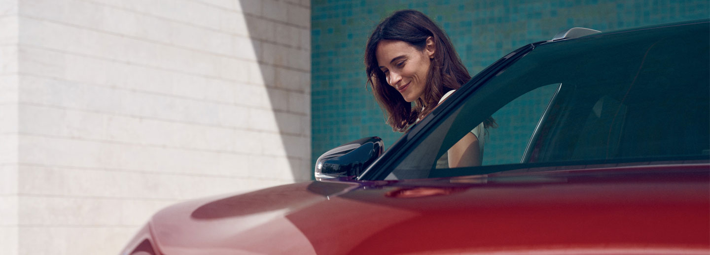 Lady standing by the side of a red car