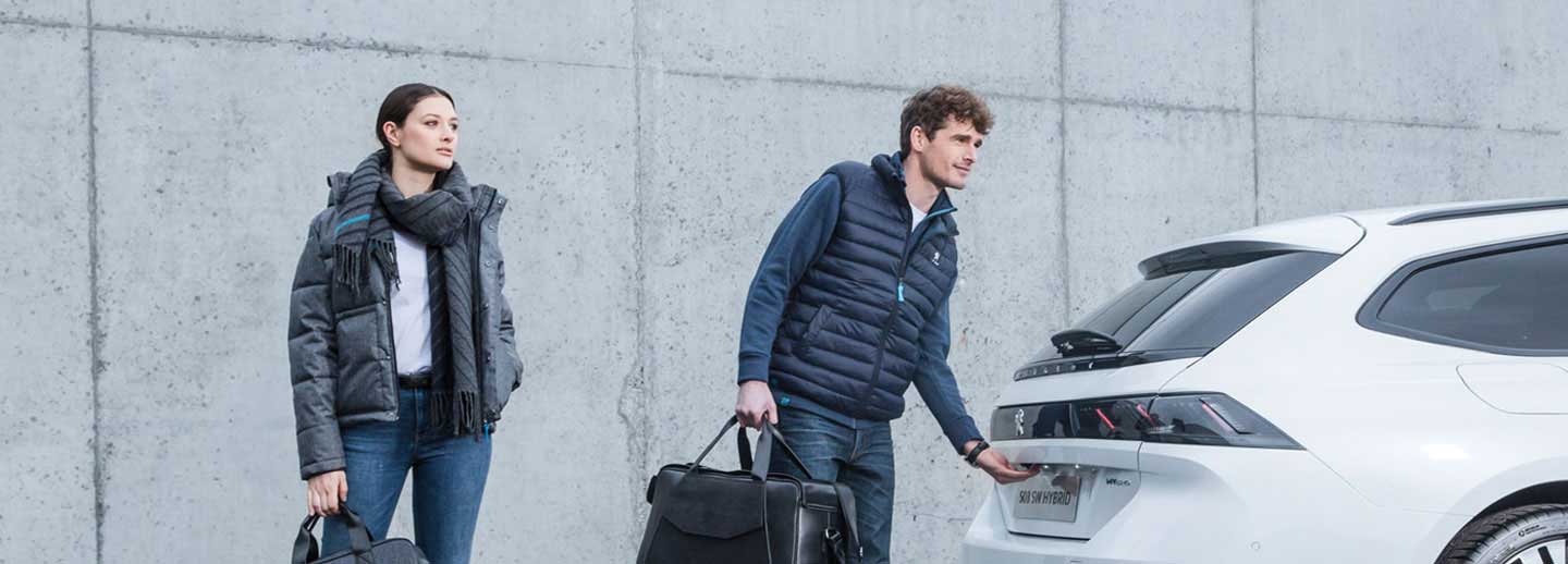Couple opening the boot of a white Peugeot 508 SW