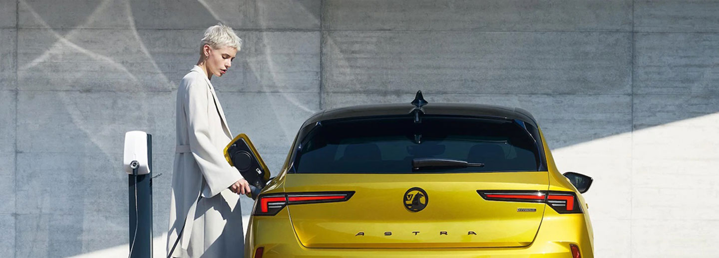 Lady charging Vauxhall Astra in Electric Yellow