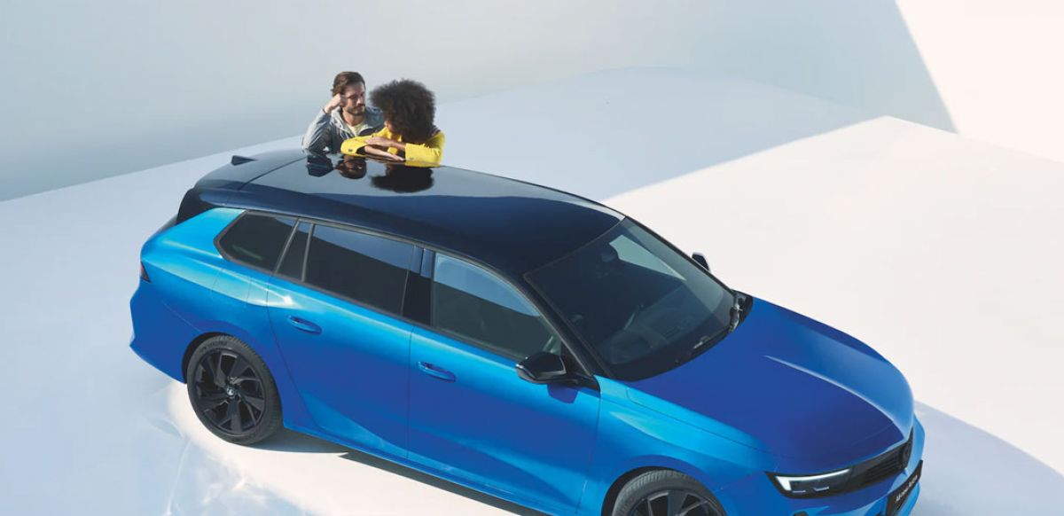 Couple leaning on Vauxhall Astra Space Tourer in Cobalt Blue