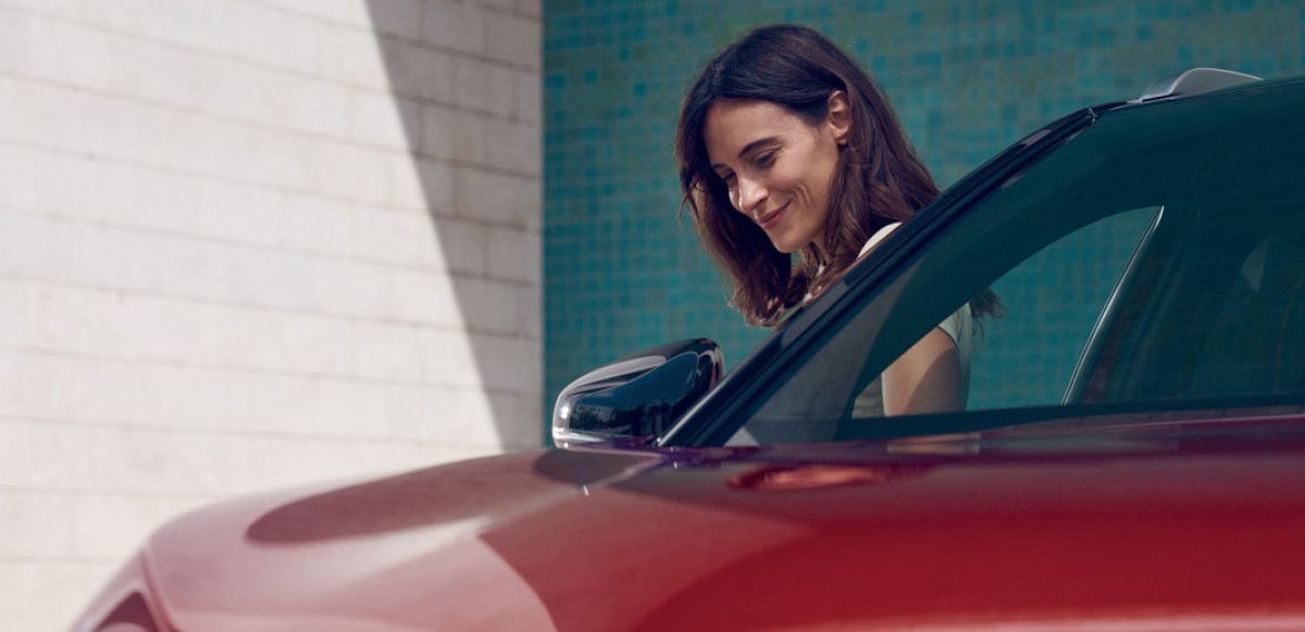 Lady standing by the side of a red car
