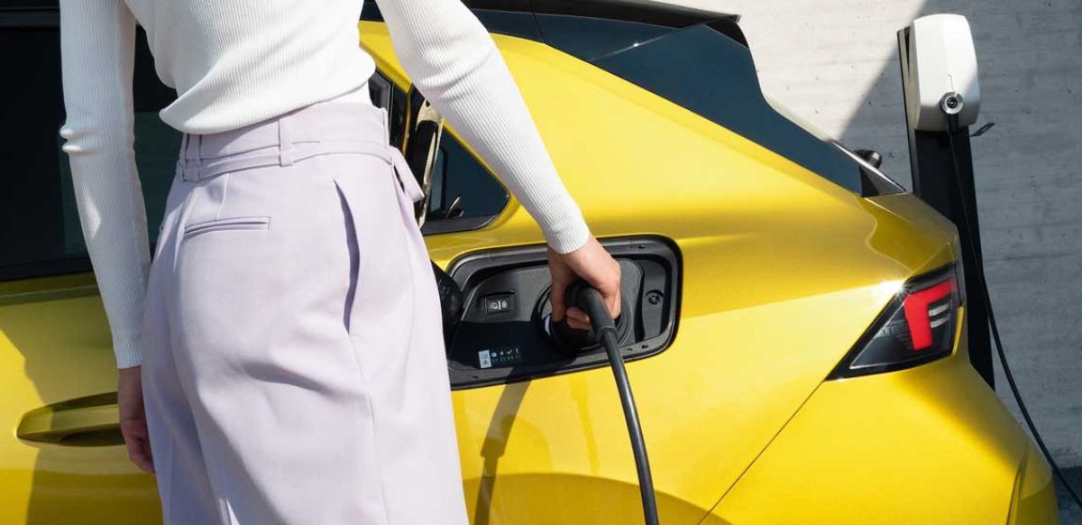 Lady charging a yellow Corsa-e