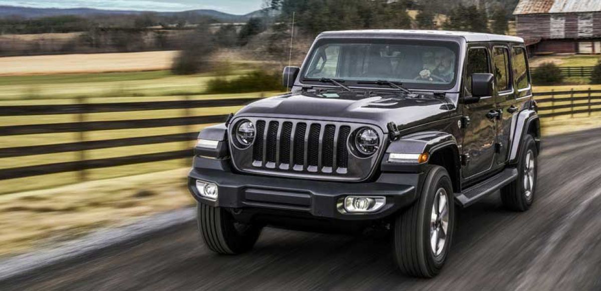 Black Jeep on a country road surrounded by fields
