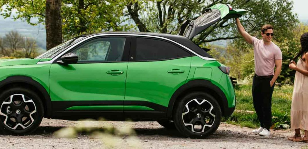 Couple standing at the rear of a Vauxhall Mokka in iconic green