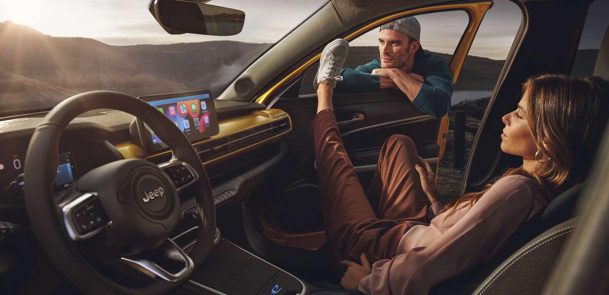  Couple sitting inside a parked yellow Jeep Connettivita