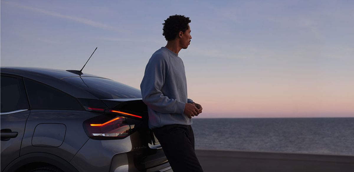 Man leaning on a SPOTICAR car looking out to the sea