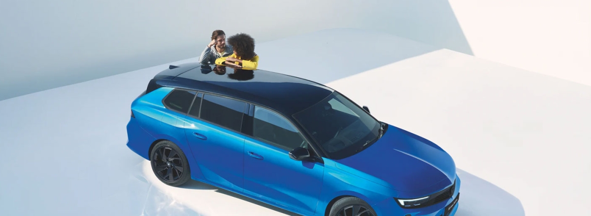 Couple leaning on Vauxhall Astra Space Tourer in Cobalt Blue
