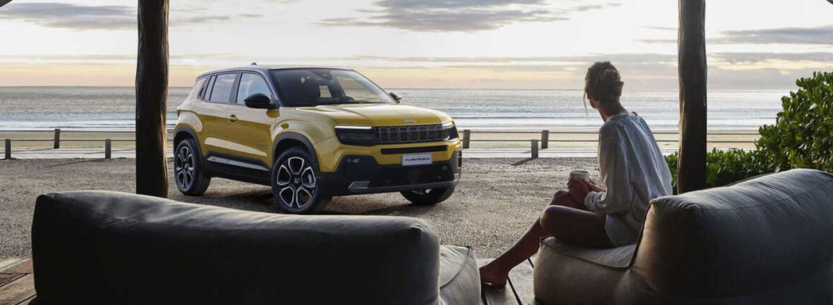 Lady sitting on beach relaxing with Jeep Avenger