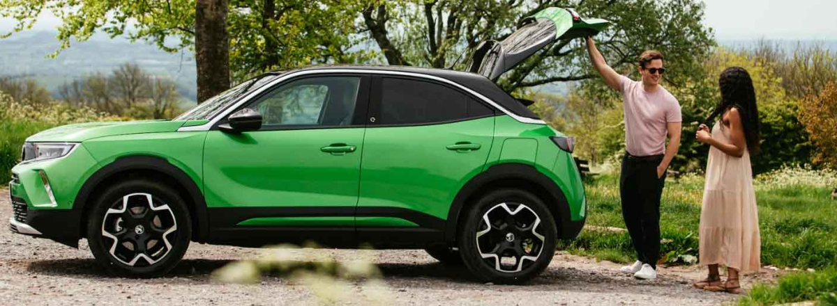 Couple standing at the rear of a Vauxhall Mokka in iconic green