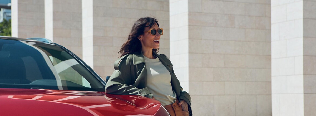 A lady leaning on a red Peugeot
