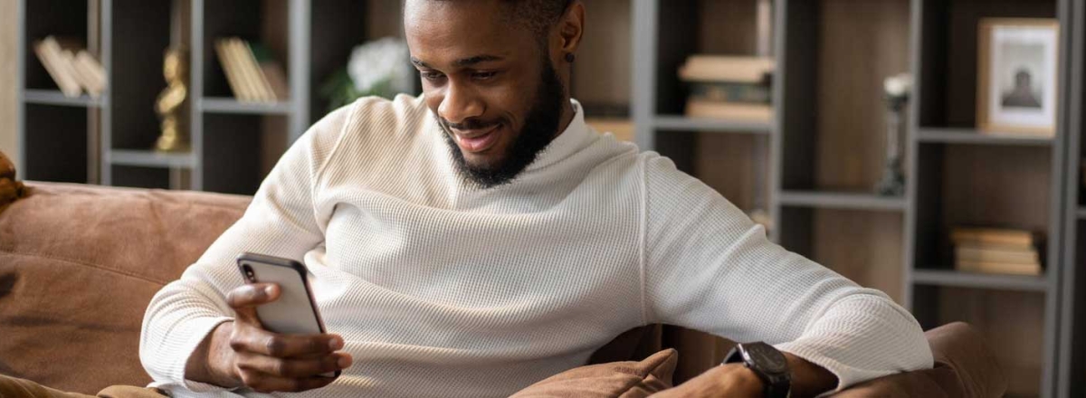 Man sitting on sofa looking at mobile phone