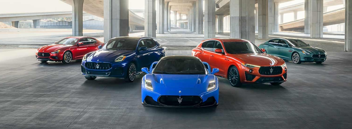 Red, grey, blue, orange and green Maserati's lined up under a bridge