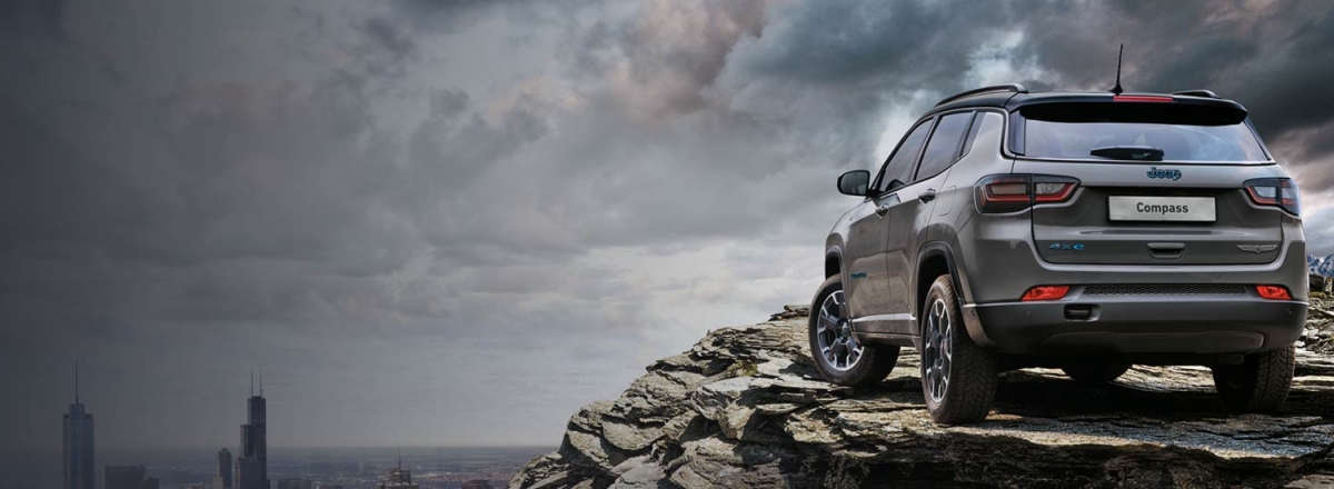 Grey Jeep Compass parked on mountain overlooking city
