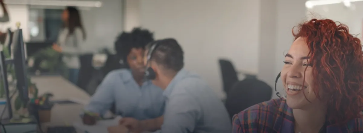 A lady with red hair on the phone in an office.
