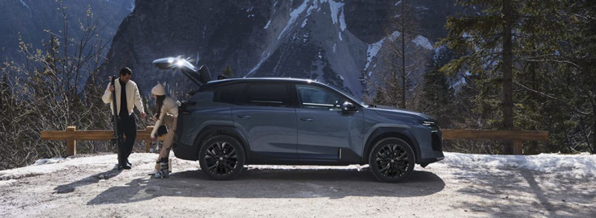 Couple stood behind a Citroen C5 Aircross in Astoria Green with Mountains in the background.