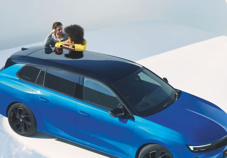 Couple leaning on Vauxhall Astra Space Tourer in Cobalt Blue