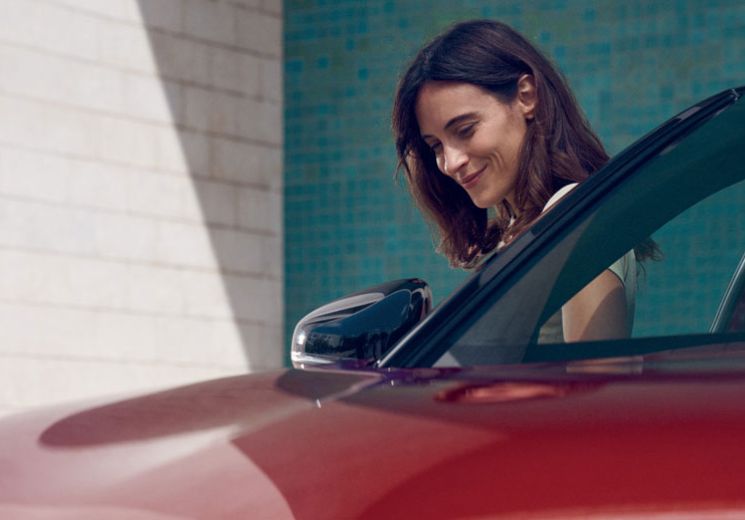 Lady standing by the side of a red car