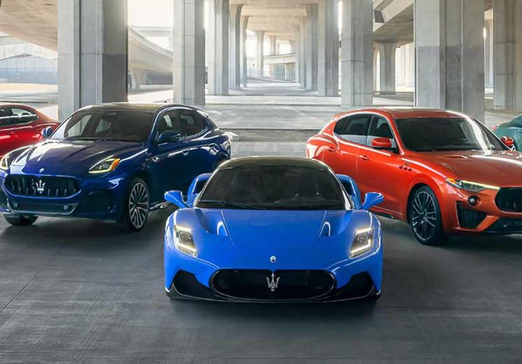 Red, grey, blue, orange and green Maserati's lined up under a bridge