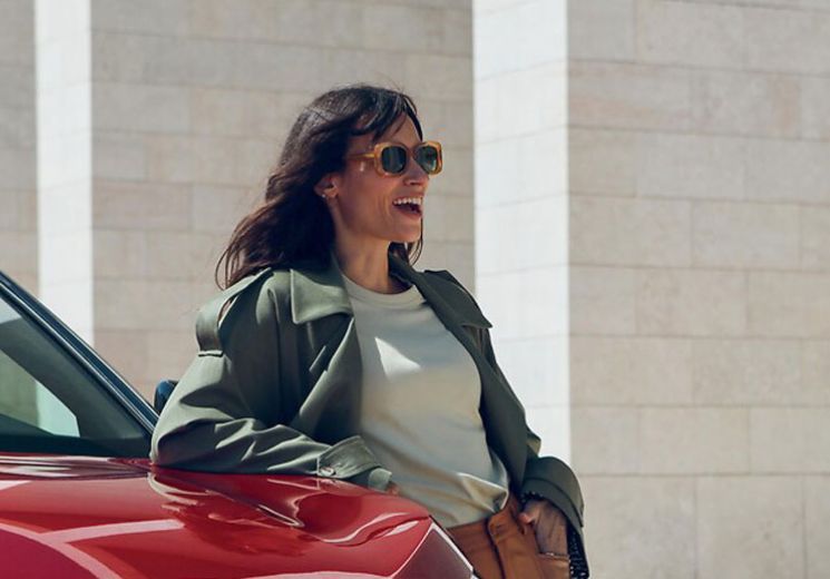 A lady leaning on a ultimate red Peugeot 3008