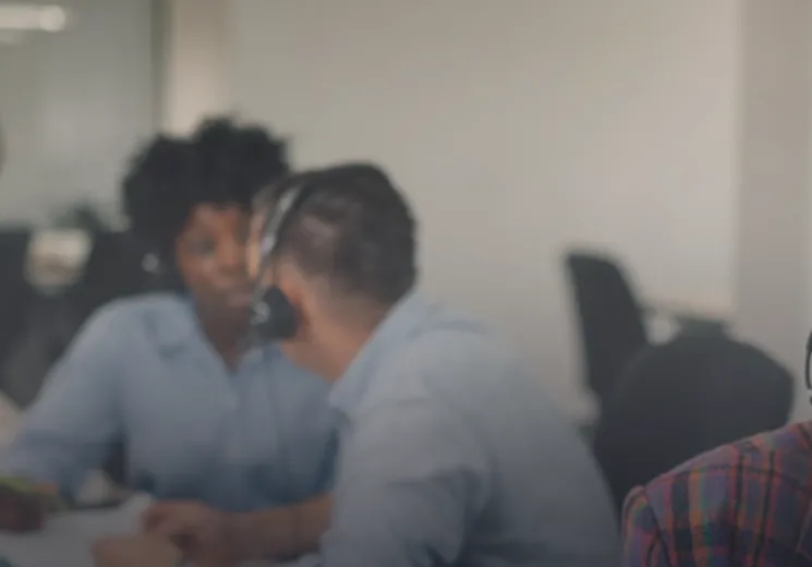 A lady with red hair on the phone in an office. 