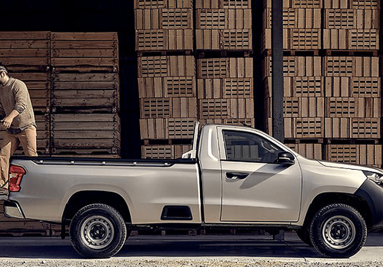 Side view of a man loading cargo into the bed of a Peugeot Landtrek.