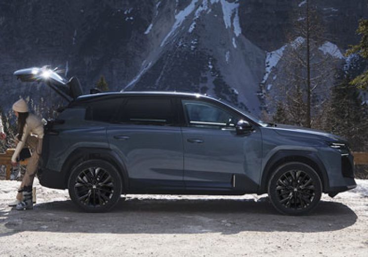 Couple stood behind a Citroen C5 Aircross in Astoria Green with Mountains in the background.