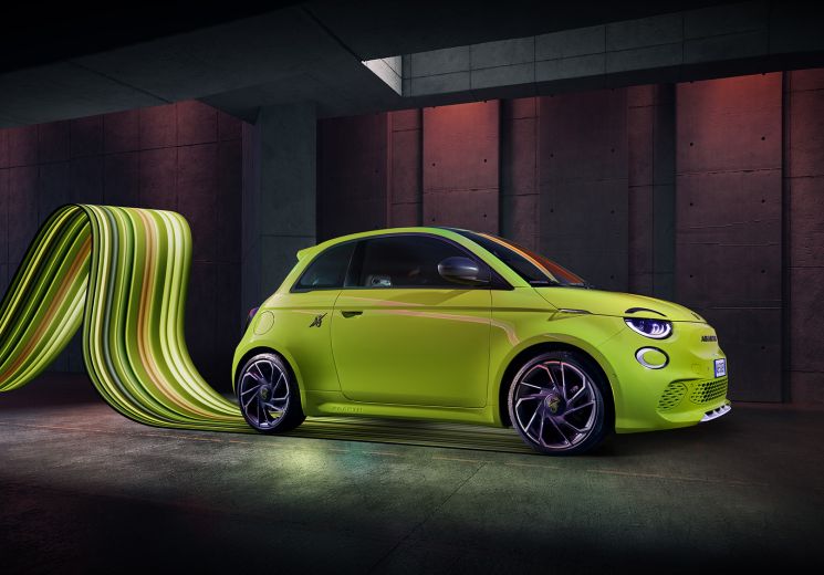 Lime green Abarth electric car parked in front of a modern architectural backdrop with curved green design elements.