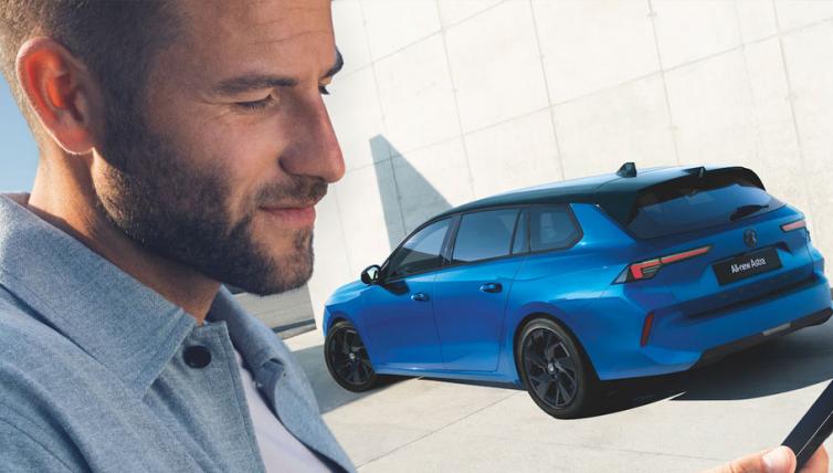 Man standing with phone by Vauxhall Astra in Cobalt Blue