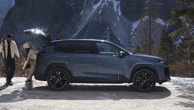 Couple stood behind a Citroen C5 Aircross in Astoria Green with Mountains in the background.