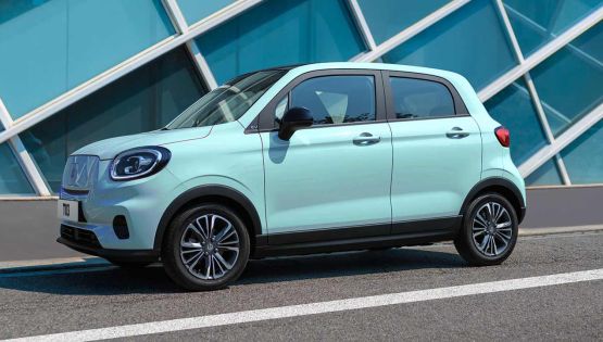 Caribbean Blue Leapmotor T03 electric hatchback parked outside a contemporary building.