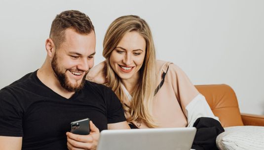 A couple sitting on the sofa looking at a laptop