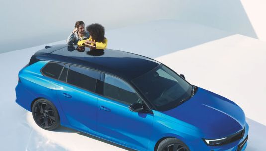 Couple leaning on Vauxhall Astra Space Tourer in Cobalt Blue
