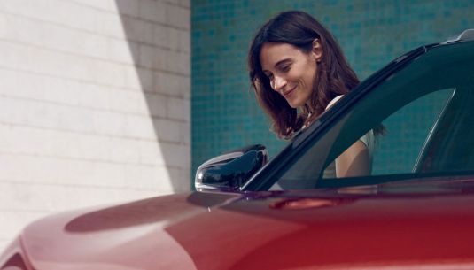 Lady standing by the side of a red car
