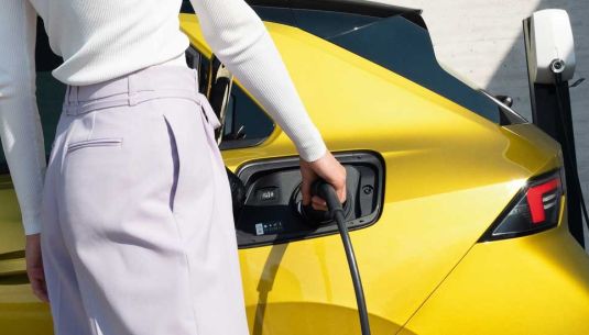 Lady charging a yellow Corsa-e