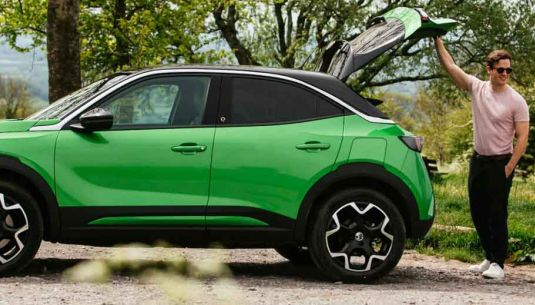 Couple standing at the rear of a Vauxhall Mokka in iconic green