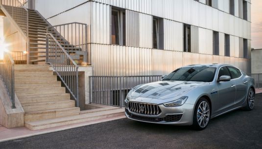 Silver Maserati outside a white building