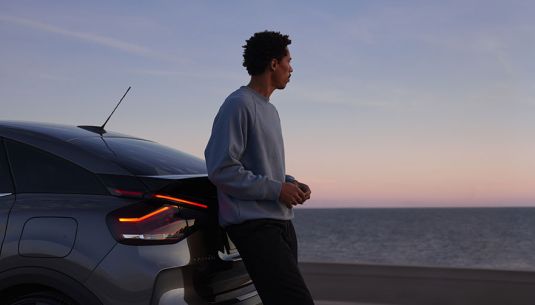 Man leaning on a SPOTICAR car looking out to the sea