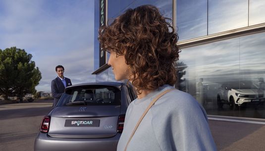 A couple outside SPOTICAR retailer looking at a car