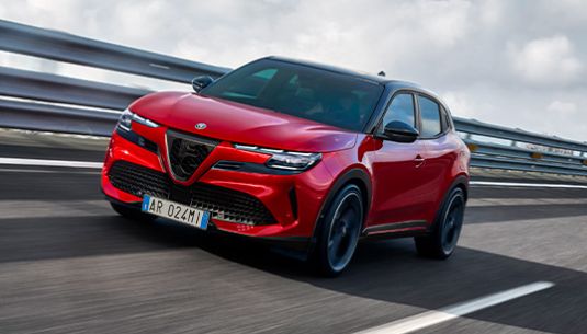 An Alfa Romeo Junior in Brera Red driving on a track.