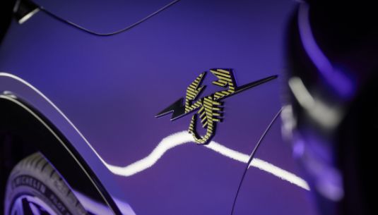 A close up of the Scorpionissima badge on a Hypnotic Purple Abarth 600e.