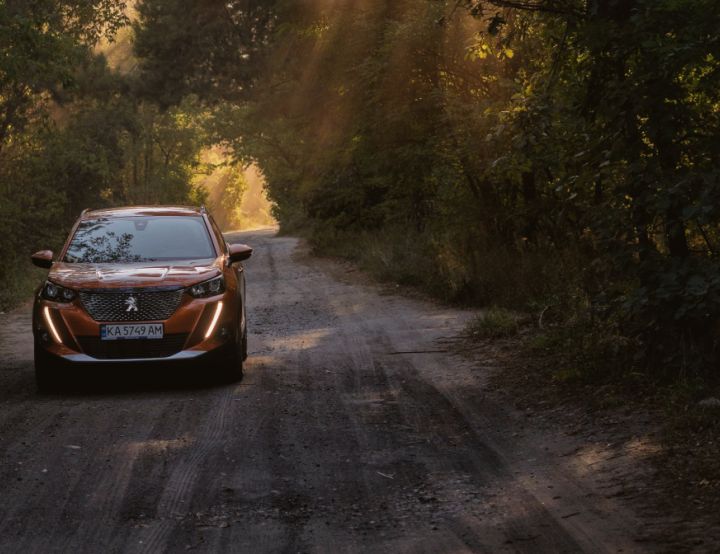 Orange Peugeot driving on a dark road