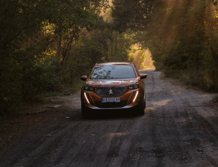 Orange Peugeot driving on a dark country road