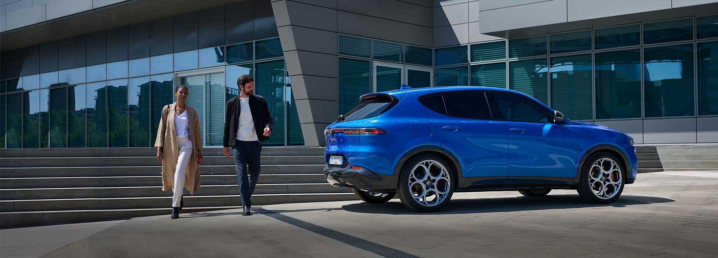 Couple walking away from Alfa Romeo Tonale in Blue