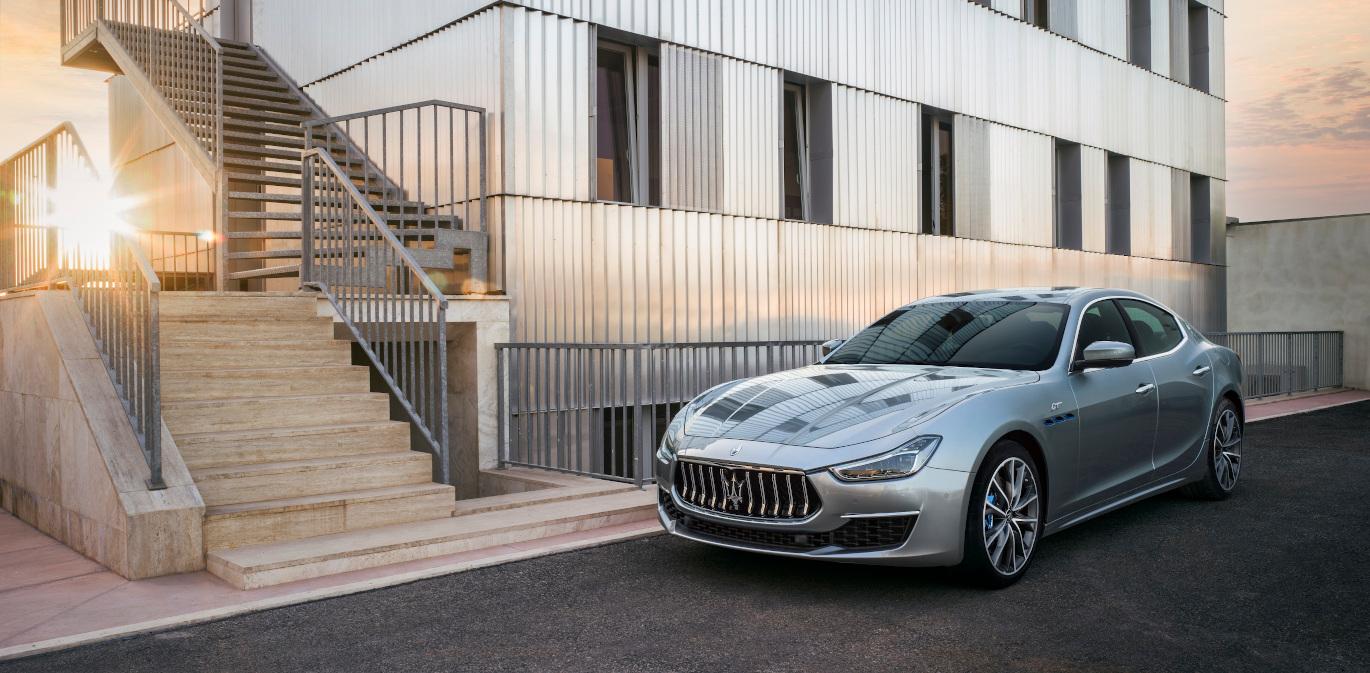 Silver Maserati outside a white building