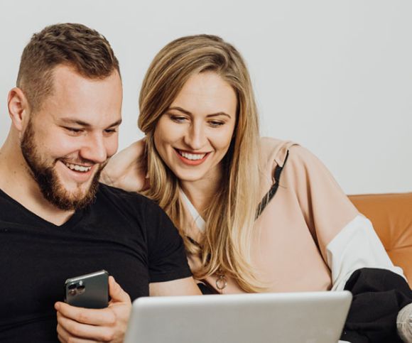 A couple siting on the sofa looking at a laptop