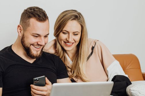 A couple sitting on the sofa looking at a laptop