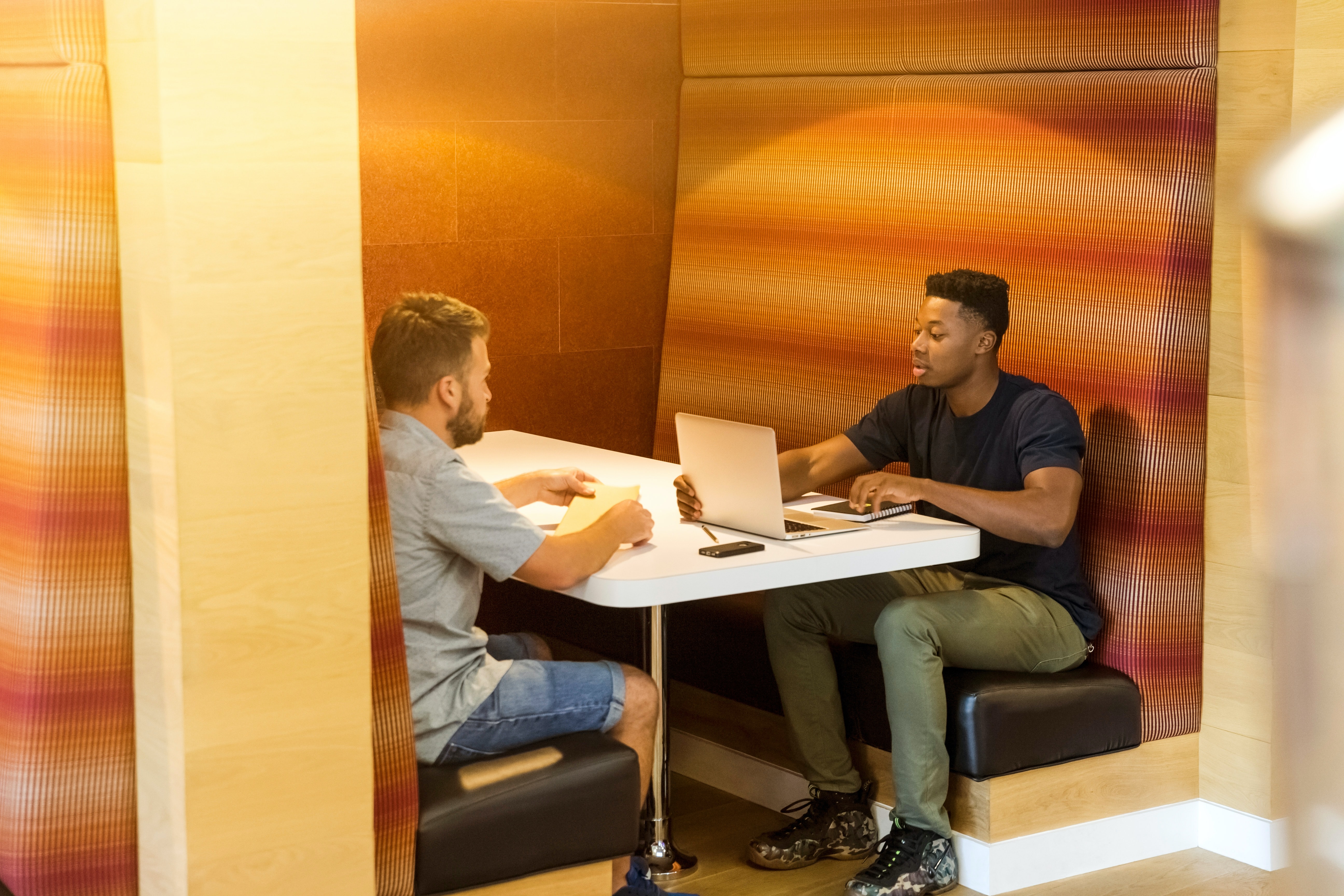 Two people sat at a desk talking